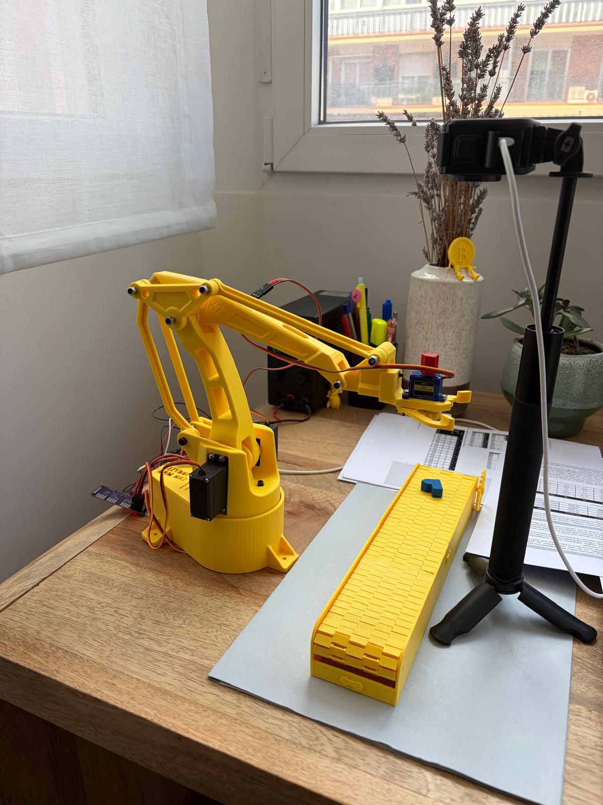 The hardware setup showing the overhead camera and the EEZYbotARM ready for multimodal commands.